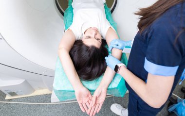 Radyolog, bilgisayarlı tomografi odasında bir kadın hasta ile birlikte.