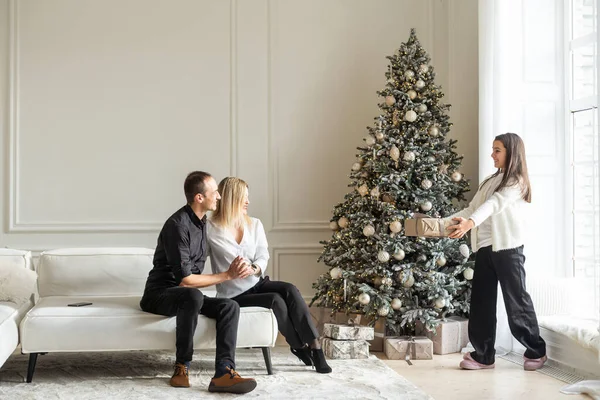 Mutlu Noeller ve mutlu tatiller. Anne, baba ve çocuk hediye değiş tokuşu. Ebeveynler ve kızları kapalı alanda eğleniyorlar. Odada hediyeleri olan sevgi dolu bir aile. Yüksek kalite fotoğraf