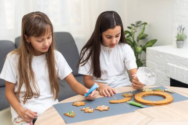 İki kız kardeş Noel kurabiyeleri yaptıktan sonra mutfakta oynuyorlar, masaya ve yüzlerine un çiziyorlar. Noel, yeni yıl konsepti. Yüksek kalite fotoğraf