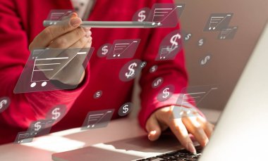 Çevrimiçi alışveriş ve e-ticaret kavramı. Alışveriş arabası simgesi olan dizüstü bilgisayar kullanan genç bir kadın, çevrimiçi mağazadan sipariş veren, internetten alışveriş yapan, klavyede yazı yazan sanal ekranda konsept kullanan bir kadın.