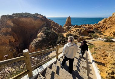 Carvoeiro gün batımında kayalıklar boyunca yürür. Carvoeiro, Portekiz. 30 Kasım 2025. Yüksek kalite fotoğraf