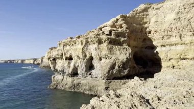 Carvoeiro, Portekiz 'in güzel manzarası, kayalıklarda beyaz evler, okyanusta yelken açan tekneler ve kumlu bir plaj. Yüksek kalite 4k görüntü