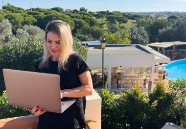 Havuz başında dizüstü bilgisayarı olan gülümseyen genç bir kadın. Yüksek kalite fotoğraf