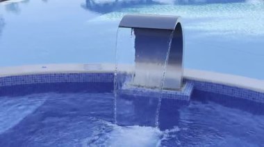 Boş yüzme havuzu, şelale jeti, jakuzi, kaplıca ve sağlık merkezi. Sahil tatili, otel konsepti. Mavi temiz deniz suyu havuzunda yansıma. Şelaleli kaplıcada rahatlama havuzu. Yüksek kalite fotoğraf