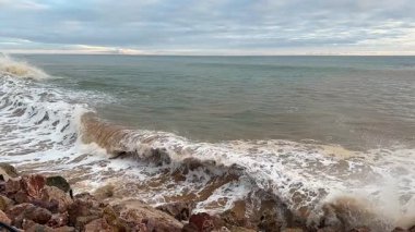 Dinamik deniz manzarası dalgaların engebeli kayalara çarptığını gösteriyor. Her yerde su sıçramaları ve köpükler yaratıyor. Yüksek kaliteli FullHD görüntüler