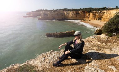 Kızıl kayalıkları ve kayalıkları olan güzel kumlu bir sahil. Günbatımında Praia do Barranco, Praia do Pontal, Algarve, Portekiz 'deki Atlantik kıyısında sığ dalgalarla birlikte. Yüksek kalite fotoğraf