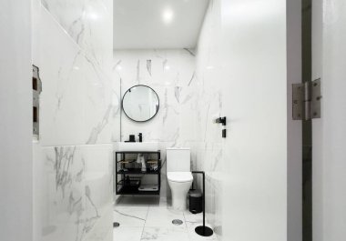 Mermer tezgahlı beyaz bir banyo, siyah musluklar ve siyah mermer kaplamalı bir duş. Yüksek kalite fotoğraf