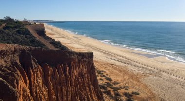 Atlantik 'teki kumlu sahil. Kum taşı kayalıkları olan bir sahilin gün batımında manzara. Albufeira, Algarve, Portekiz yakınlarındaki Praia 'nın sarı sahilinde gelgit var. Yüksek kalite fotoğraf