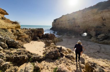 Anne ve kızı kayaların yakınındaki sahilde yürüyüş yapıyor. Arkadan bak. Praia de Albandeira, Portekiz 'in Algarve sahilinde bir plaj. Yüksek kalite fotoğraf