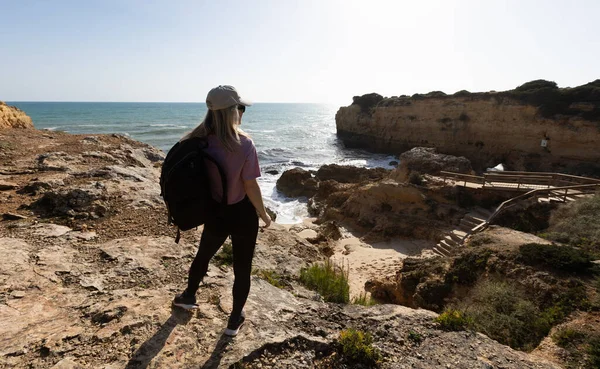 Güneşli ve rüzgarlı bir yaz gününde Atlantik Okyanusu 'nun üzerinde uçurumun kenarında duran orta yaşlı güzel bir yürüyüşçü kadın. Arkadan bak. Yüksek kalite fotoğraf