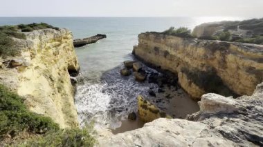 Okyanusun manzaralı bir manzarası kayalık bir mağaranın açılması, dalgaların parlak mavi bir gökyüzünün altında, tüylü bulutların altında bir uçuruma çarpması. Yüksek kalite fotoğraf