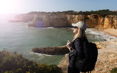 Portekiz, Praia do Barranco 'da okyanusun üzerindeki bir uçurumda güzel bir kadın oturuyor. Yüksek kalite fotoğraf