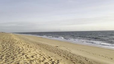 Kızıl kayalıkları ve kayalıkları olan güzel kumlu bir sahil. Günbatımında Atlantik kıyısında Algarve, Portekiz 'de sığ dalgalarla birlikte. Yüksek kalite fotoğraf