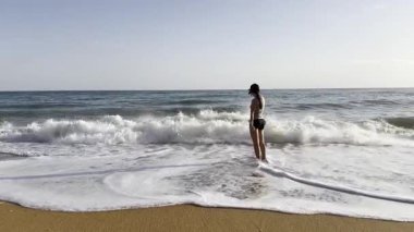 Portekiz, Algarve 'deki kayalık sahil boyunca Atlantik dalgalarıyla yüzleşen bir insan. Yüksek kalite 4k görüntü