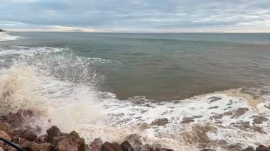 Dinamik deniz manzarası dalgaların engebeli kayalara çarptığını gösteriyor. Her yerde su sıçramaları ve köpükler yaratıyor. Yüksek kaliteli FullHD görüntüler
