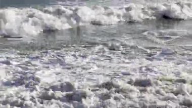 Sahildeki deniz suyu yaz arkaplanı. Kum plajı çöl dokusu. Beyaz köpüklü kumlu deniz manzaralı. Yüksek kalite 4k görüntü