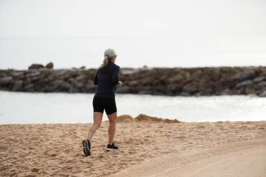 Sabahları sahilde koşan bir kız. Rahatla ve denizde koşmaktan mutlu ol. Yazın. Yüksek kalite fotoğraf