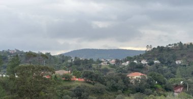 Nehir kenarındaki tepedeki manzaralı kır evi bulutlu gökyüzünün altında. Yüksek kalite fotoğraf