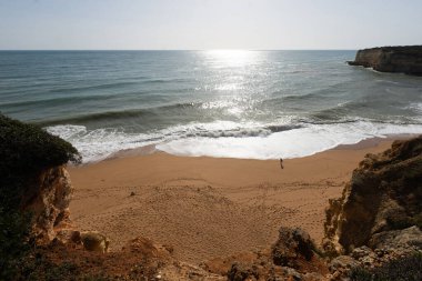 Kumlu Algarve plajı, dramatik bir gökyüzü altında kaya oluşumlarına çarpan dalgalar. Huzurlu bir manzara, doğayı keşfetmek, kıyı titreşimleri. Yüksek kalite fotoğraf