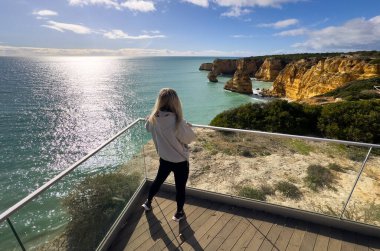 Portekiz, Algarve 'deki Marinha Sahili' nin tepesinden Atlantik Okyanusu 'nun tadını çıkaran bir kadın. Yüksek kalite fotoğraf