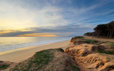 Portekiz Praia de Loule Velho 'nun görkemli kayalıkları ve altın kumları sakin bir günbatımında çarpıcı kaya oluşumlarına çarpar. Yüksek kalite fotoğraf