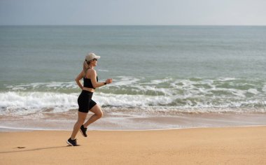 Kadın, plajda, arkada ya da dışarıda rutin bir çalışma için koşuyor ve çalışıyor. Sağlık, kardiyo müsabakası ve okyanus kıyısında koşmak için yazın insan, egzersiz ve spor. Yüksek kalite fotoğraf