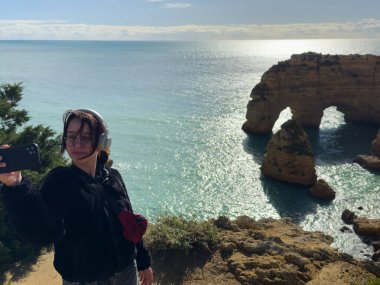 Cliffside Okyanus manzarasında selfie çeken kız gezgin Arcos Naturais da Praia da Marinha Lagoa, Algarve. Yüksek kalite fotoğraf