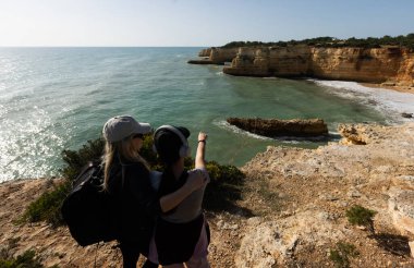 Kızıl kayalıkları ve kayalıkları olan güzel kumlu bir sahil. Günbatımında Praia do Barranco, Praia do Pontal, Algarve, Portekiz 'deki Atlantik kıyısında sığ dalgalarla birlikte. Yüksek kalite fotoğraf