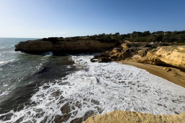 Güneşli ve açık bir bahar sabahında, gün doğumundan hemen sonra, Arnavutdeira sahilinin kayalıkları. Albandeira, Portekiz. Yüksek kalite fotoğraf