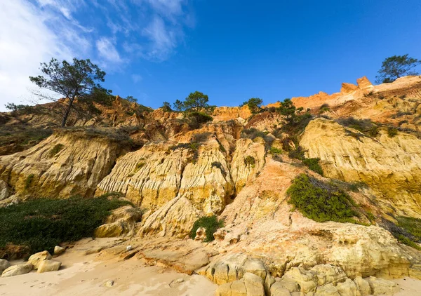 Turuncu ve sarı tortulu kaya tabakaları olan engebeli uçurum, sert çalılarla süslenmiş. Parçalı bulutlu gökyüzünün altında aşınmış dokular doğanın saf güzelliğini sergiliyor. Yüksek kalite fotoğraf
