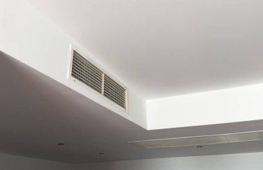 Beyaz, temiz otel odası arka planında tavana monte edilmiş havalandırma sistemi. Otel odasının havalandırma ızgarası duvarda. Yüksek kalite fotoğraf
