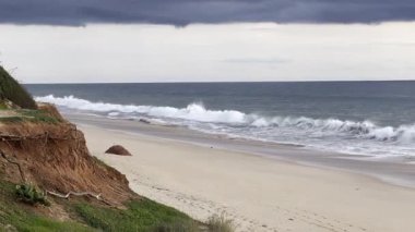 Kızıl kayalıkları ve kayalıkları olan güzel kumlu bir sahil. Günbatımında Praia de Loule Velho, Algarve, Portekiz 'de Atlantik kıyısında sığ dalgalarla birlikte. Yüksek kalite fotoğraf