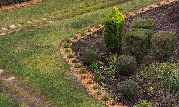 Curvy pathway in the flowering garden with shaped trees. High quality photo