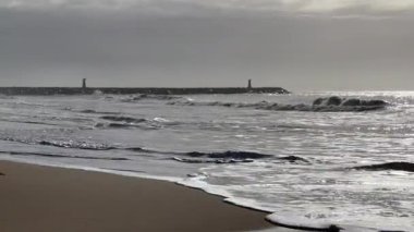 Hafif okyanus dalgalarının kıyıya vurduğu kumlu bir sahil altın öğleden sonra güneş ışığı altında soluk uzak tepeler hafif bulutlu bir gökyüzünün altında ufuk çizgisi oluştururken. - Evet. Yüksek kalite fotoğraf
