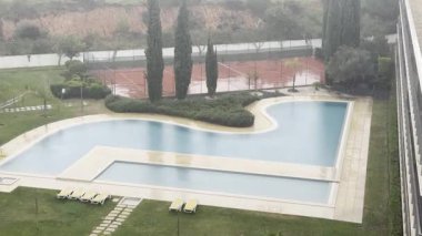 Güverte sandalyeli yüzme havuzunun yanındaki dinlenme odasının penceresinden bak. Muhteşem arka bahçenin iç tasarımı ve dinlenmek için geniş bir avlu. Yüksek kalite 4k görüntü