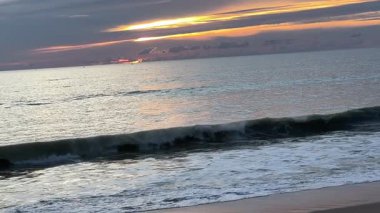 Gökyüzünde harmanlanan parlak altın ve mor tonlarıyla okyanusun üzerinde gün batımı ve renkleri yansıtan sakin dalgalar kıyı manzarasının huzurlu ve resimsel bir görüntüsünü sunuyor. Tayland. - Evet. Yüksek kalite 4k görüntü
