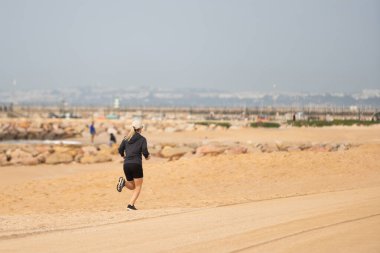 Kumsalda koşan şortlu genç bir kadın. Kız sahile koşuyor, spor yaşam tarzı. Yüksek kalite fotoğraf