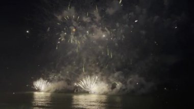 Koyu renkli gökyüzüne karşı kaleydoskop şeklinde muhteşem havai fişekler patlayarak yerel kutlamalar boyunca izleyicileri büyüledi. Patlamalar heyecan dolu canlı bir atmosfer yaratıyor. Yüksek kalite 4k görüntü