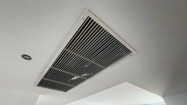 Beyaz, temiz otel odası arka planında tavana monte edilmiş havalandırma sistemi. Otel odasının havalandırma ızgarası duvarda. Yüksek kalite fotoğraf