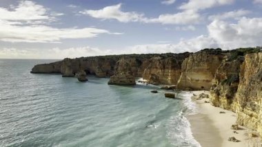 Kayalık kayalıkları, bitki örtüsü ve mavi bulutlu gökyüzü olan kumsal. Yüksek kalite fotoğraf