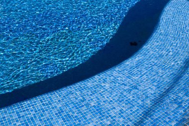 Kavisli mozaik, parlak bir yaz gününde temiz mavi suyla dolu bir yüzme havuzunun girişi olarak merdivenlerle döşenmiş. Yüksek kalite fotoğraf