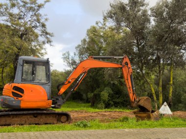 Kazı makinesi, orman arka planındaki tepeleri kazıyor ve açık mavi gökyüzünü kazıyor. Yüksek kalite fotoğraf