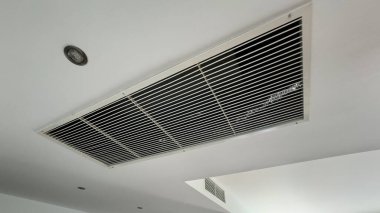 Beyaz, temiz otel odası arka planında tavana monte edilmiş havalandırma sistemi. Otel odasının havalandırma ızgarası duvarda. Yüksek kalite fotoğraf