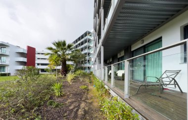 Minimalist sandalyeli modern bir teras ve cam duvarlar ve beton dokularla çerçevelenmiş ahşap süslemeli küçük bir masa. Yüksek kalite fotoğraf