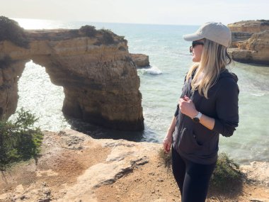 Panoramik okyanus manzaralı bir sahilde selfie çeken genç kadın Arco de Albandeira, Praia da Estaquinha, Portekiz. Yüksek kalite fotoğraf