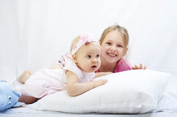 Bonito irmãzinha jogar com recém-nascido em um fundo branco Fotos De Bancos De Imagens Sem Royalties