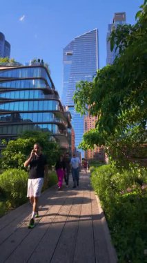 New York City, New York, ABD - 25 Mayıs 2024: Hudson Yards gökdelenleri manzaralı The Highline gezinti alanında yaz günü. Chelsea, Manhattan 'ın göbeğindeki yüksek yeşil yolda yürüyen yayalar.