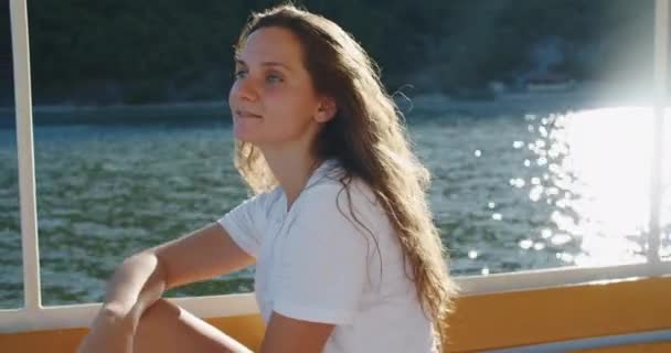 Eine junge brünette Frau segelt auf einem Boot auf einem schönen See und erkundet die Natur. Frauenporträt in Großaufnahme — Stockvideo