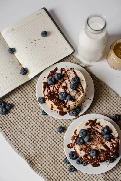 Heerlijke pannenkoeken met bosbessen, chocolade en een fles melk. Gezond eten. Ochtend lekker zelfgemaakt ontbijt, stapel pluizige en heerlijke suikervrije pannenkoeken. Witte achtergrond. — Stockfoto