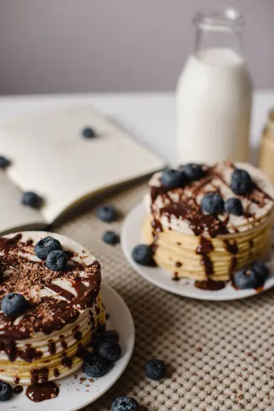 Delicious pancakes with blueberries, chocolate and a bottle of milk. Healthy eating. Morning tasty homemade breakfast, stack of fluffy and delicious sugar free pancakes. White background. — Stock Photo, Image